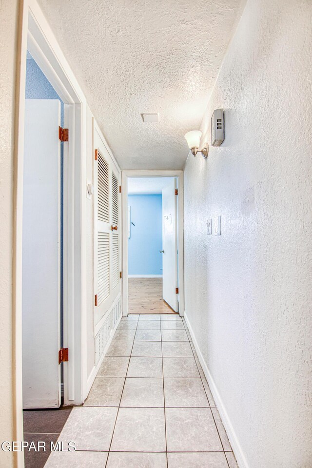 hallway with light tile patterned floors and a textured ceiling