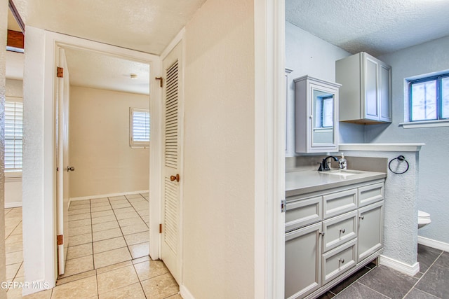 bathroom featuring tile patterned flooring, vanity, toilet, and a textured ceiling