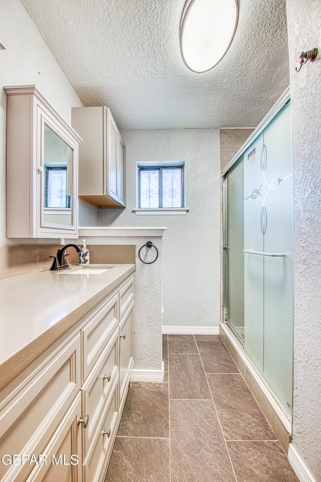 bathroom featuring a textured ceiling, vanity, and an enclosed shower