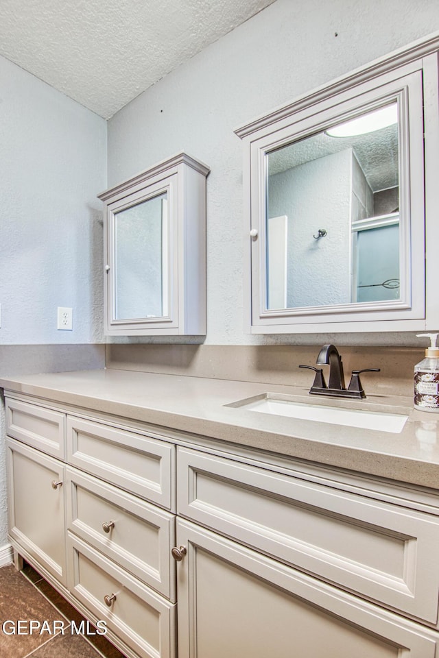 bathroom with a textured ceiling, vanity, and a shower with door