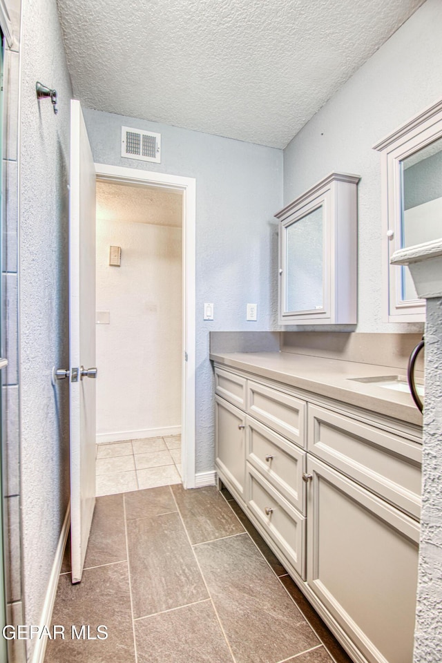 bathroom featuring tile patterned flooring, vanity, and a textured ceiling