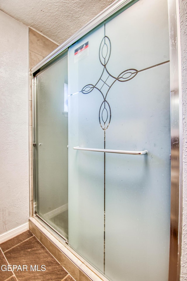 bathroom featuring a textured ceiling, hardwood / wood-style flooring, and an enclosed shower