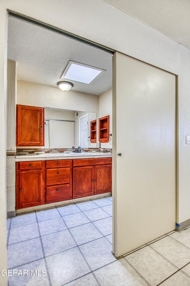 bathroom with tile patterned floors, vanity, a textured ceiling, and a skylight