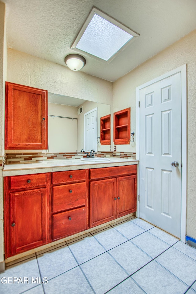 bathroom with a skylight, tile patterned flooring, vanity, and a textured ceiling