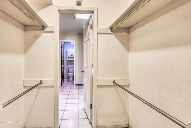 walk in closet with light tile patterned floors