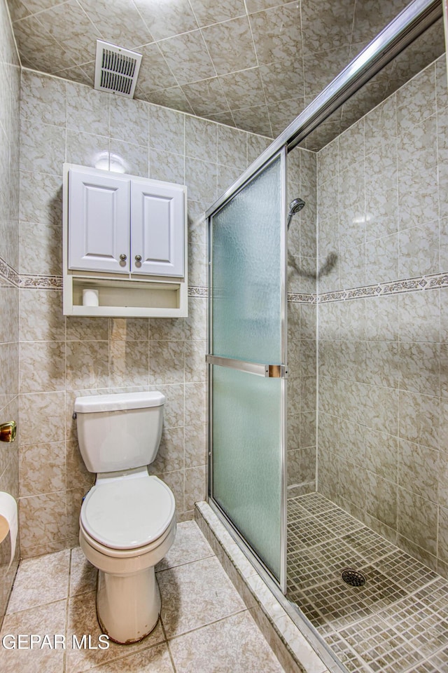 bathroom featuring walk in shower, tile patterned floors, tile walls, and toilet