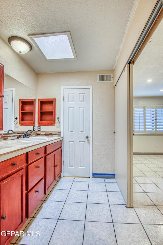 bathroom featuring tile patterned flooring, vanity, a textured ceiling, and a skylight