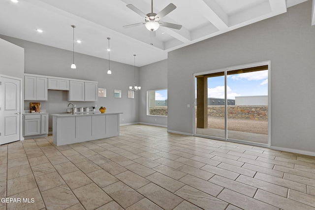 kitchen featuring white cabinets, ceiling fan with notable chandelier, an island with sink, and a high ceiling