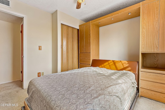 carpeted bedroom featuring a textured ceiling, a closet, and ceiling fan