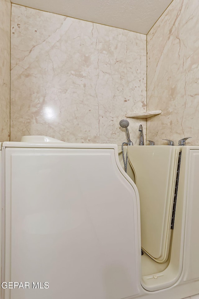 room details with a textured ceiling and washer / clothes dryer