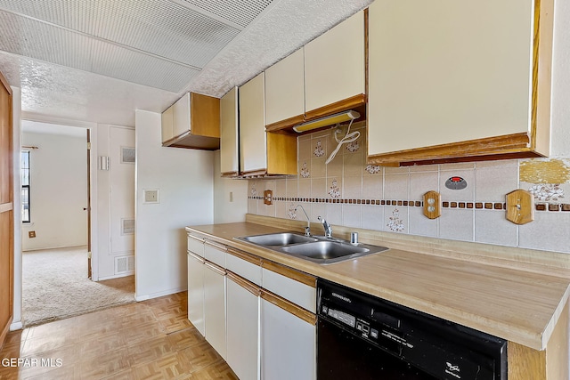 kitchen featuring dishwasher, white cabinets, sink, tasteful backsplash, and light parquet flooring