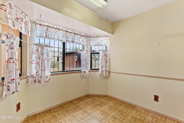 empty room with a textured ceiling and light parquet flooring