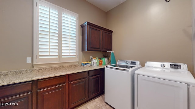 laundry room featuring cabinets, plenty of natural light, light tile patterned flooring, and washing machine and dryer