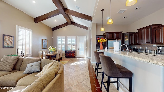 kitchen featuring a kitchen bar, decorative backsplash, stainless steel refrigerator with ice dispenser, light stone countertops, and beamed ceiling