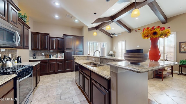 kitchen featuring dark brown cabinetry, sink, stainless steel appliances, beamed ceiling, and a center island with sink