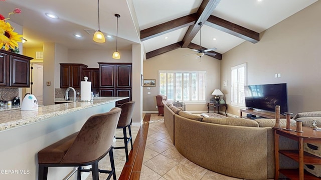 tiled living room featuring vaulted ceiling with beams, ceiling fan, and sink