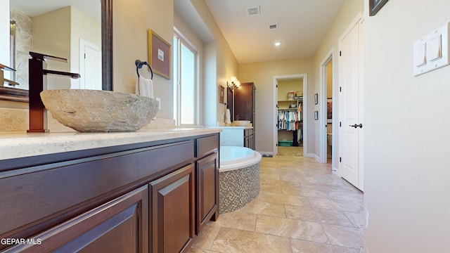 bathroom featuring tiled tub and vanity