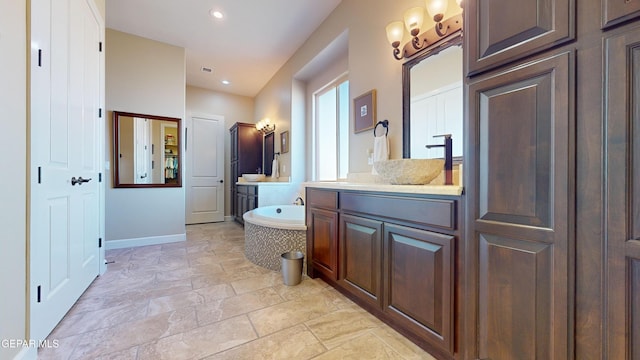 bathroom featuring tiled tub and vanity