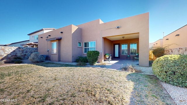 back of property with a yard and a patio