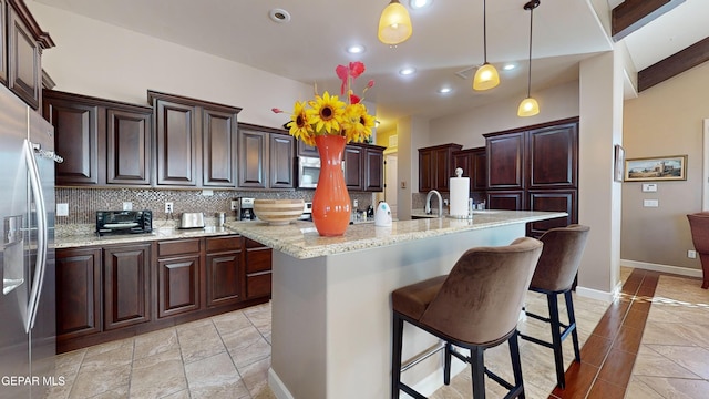 kitchen featuring sink, tasteful backsplash, decorative light fixtures, a kitchen island with sink, and appliances with stainless steel finishes