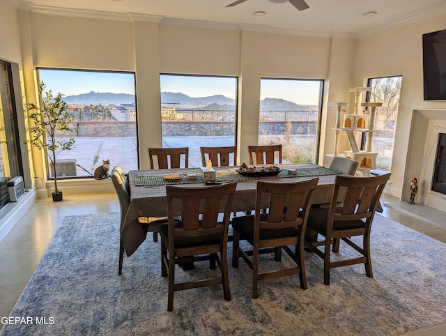 dining area featuring tile patterned flooring, a mountain view, ceiling fan, and crown molding