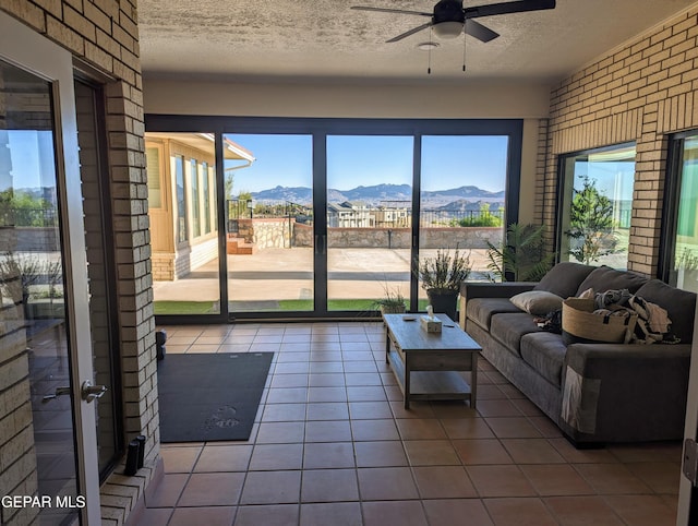 unfurnished living room with a mountain view, a textured ceiling, tile patterned floors, and ceiling fan