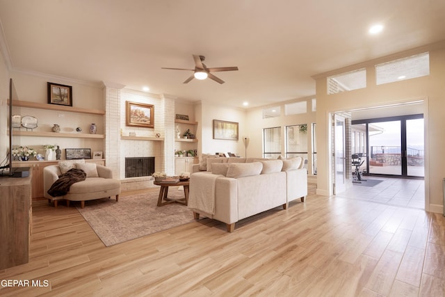 living room featuring ceiling fan, light hardwood / wood-style flooring, built in features, and a brick fireplace