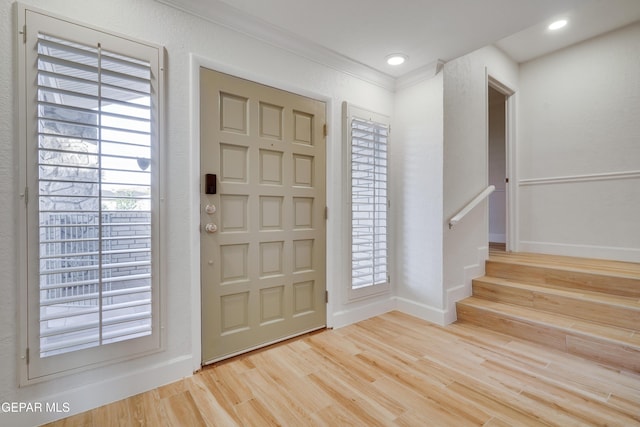 foyer entrance with crown molding and light hardwood / wood-style flooring