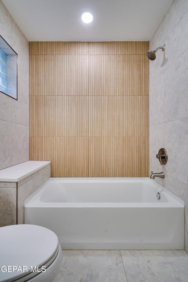 bathroom with shower / bathtub combination, toilet, and tile walls