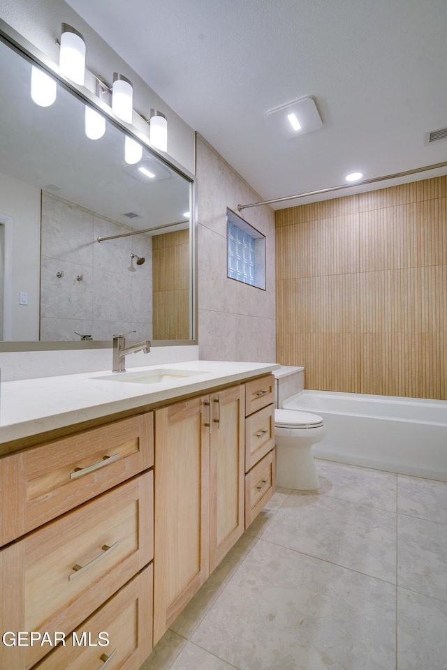 full bathroom featuring tub / shower combination, tile patterned floors, toilet, vanity, and tile walls