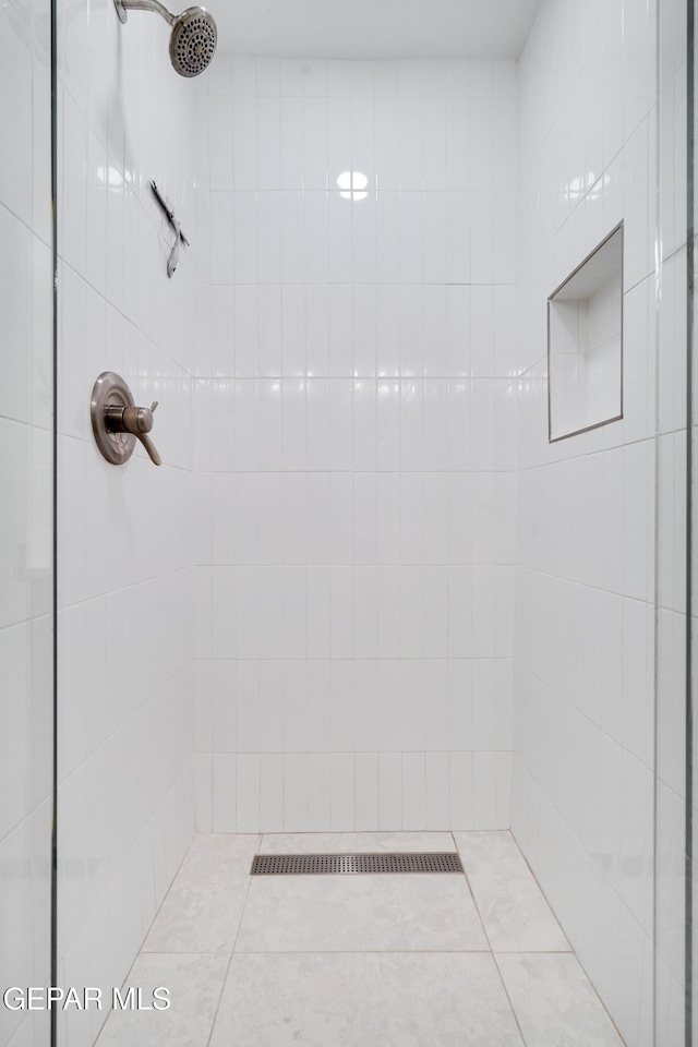 bathroom with tile patterned flooring and a tile shower