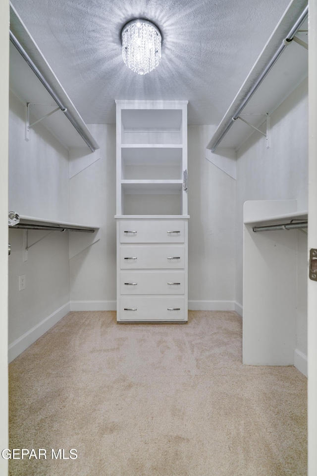 walk in closet featuring a chandelier and light colored carpet