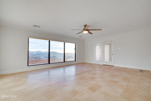 empty room with a textured ceiling, a mountain view, ceiling fan, and crown molding