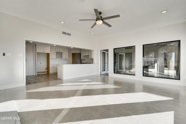 unfurnished living room featuring ceiling fan, sink, light tile patterned floors, and crown molding