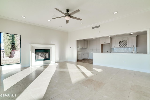 unfurnished living room featuring ceiling fan, ornamental molding, and light tile patterned floors