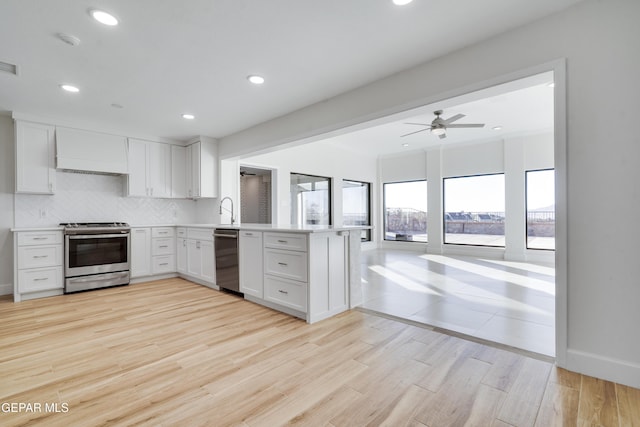 kitchen featuring backsplash, kitchen peninsula, custom range hood, appliances with stainless steel finishes, and white cabinetry