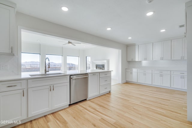 kitchen featuring stainless steel dishwasher, white cabinets, sink, and tasteful backsplash