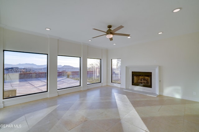 unfurnished living room with a mountain view, ceiling fan, and ornamental molding