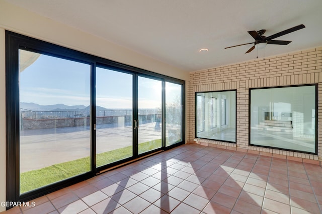 unfurnished sunroom featuring a mountain view and ceiling fan