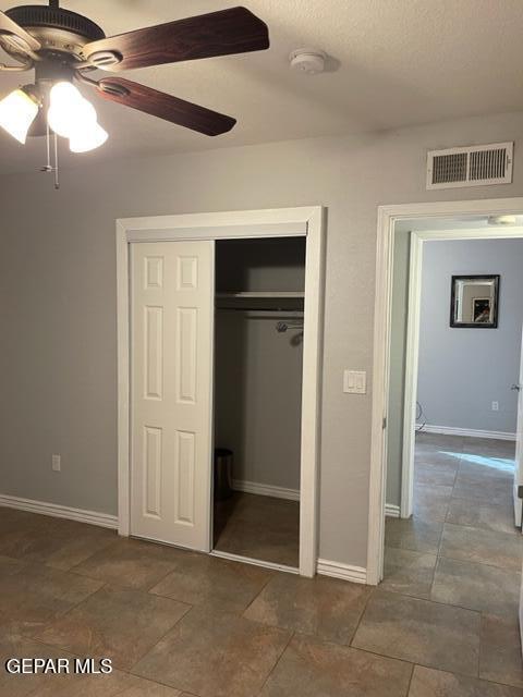 unfurnished bedroom with a textured ceiling, a closet, and ceiling fan