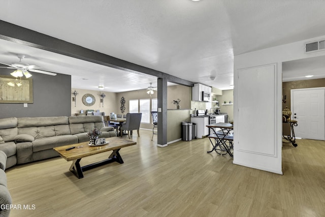 living room with beam ceiling, a textured ceiling, and light hardwood / wood-style floors