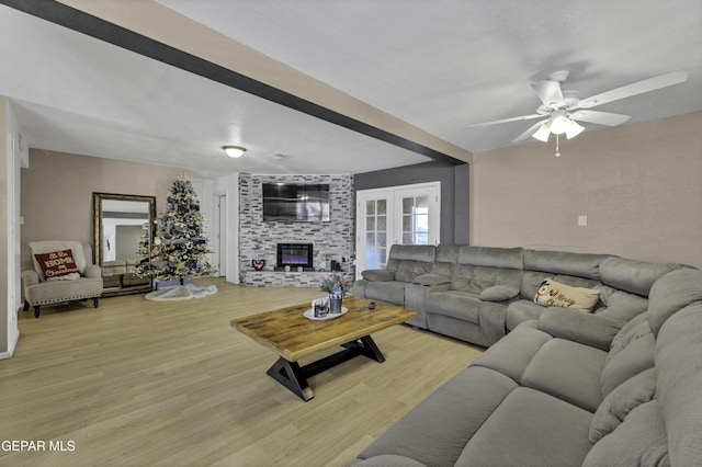 living room featuring ceiling fan, a fireplace, and light hardwood / wood-style floors