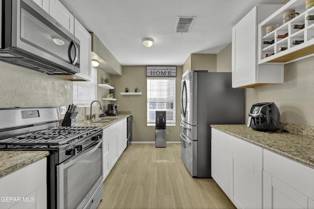 kitchen featuring light stone counters, white cabinetry, sink, and appliances with stainless steel finishes