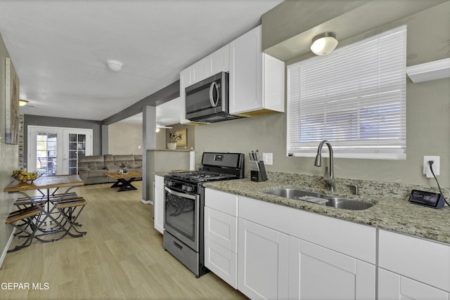 kitchen featuring white cabinetry, sink, light stone counters, light hardwood / wood-style floors, and appliances with stainless steel finishes