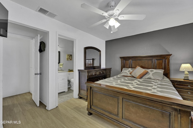 bedroom with light wood-type flooring, ensuite bathroom, and ceiling fan