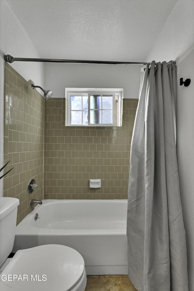 bathroom with toilet, shower / bath combo with shower curtain, and a textured ceiling