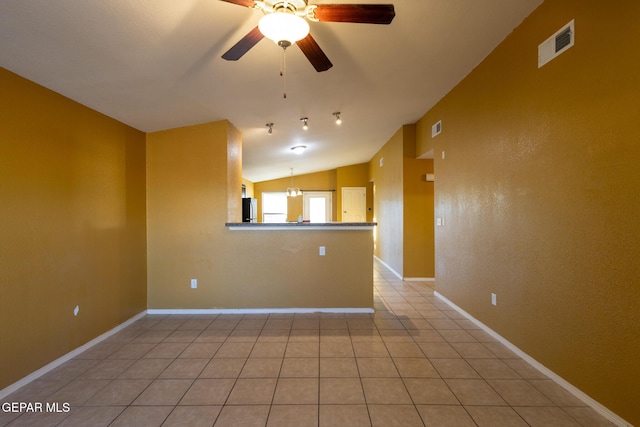 tiled empty room featuring ceiling fan with notable chandelier and lofted ceiling