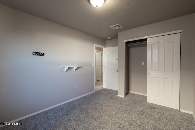 unfurnished bedroom featuring a textured ceiling, carpet floors, and a closet