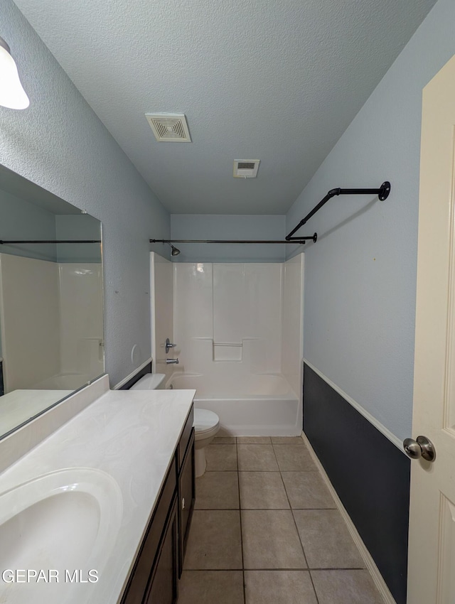 full bathroom featuring tile patterned floors, a textured ceiling, vanity, bathing tub / shower combination, and toilet