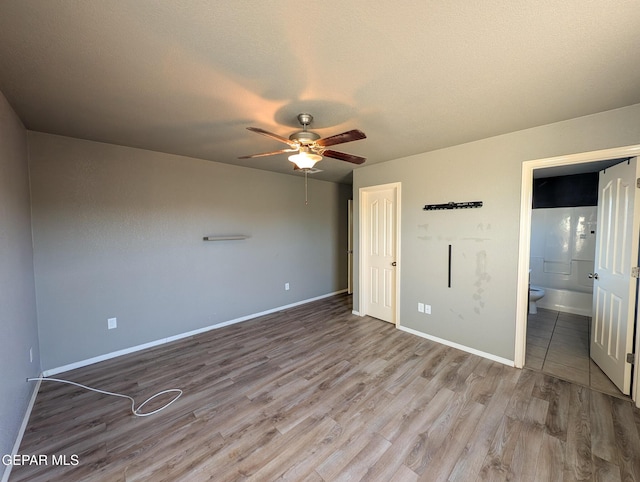 unfurnished bedroom featuring hardwood / wood-style floors, ensuite bathroom, and ceiling fan